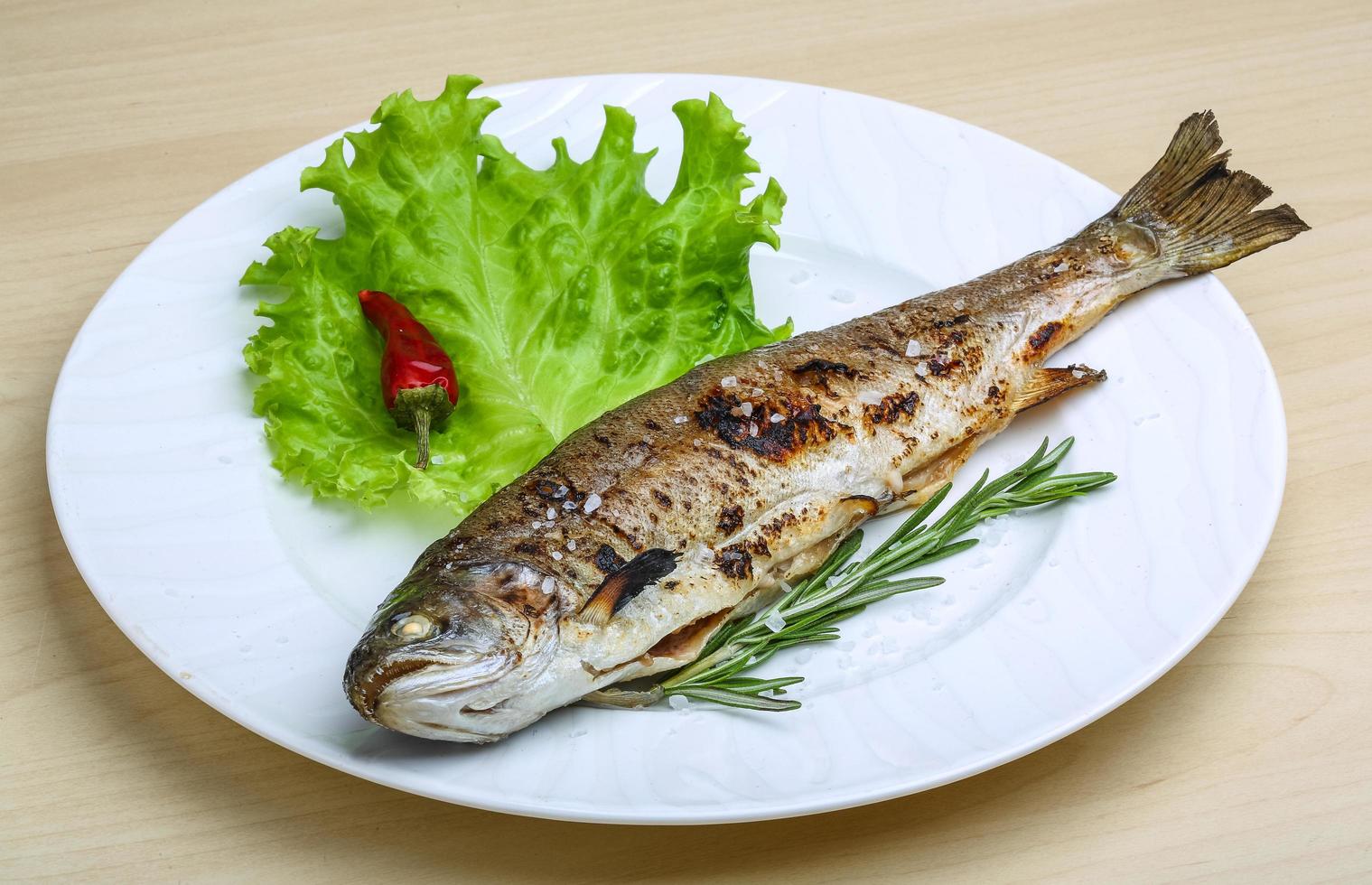 Grilled trout on the plate and wooden background photo