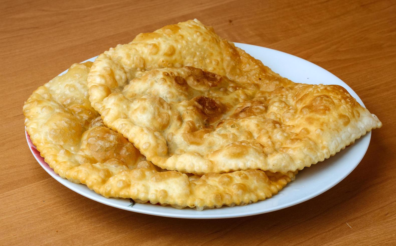 Cheburek on the plate and wooden background photo