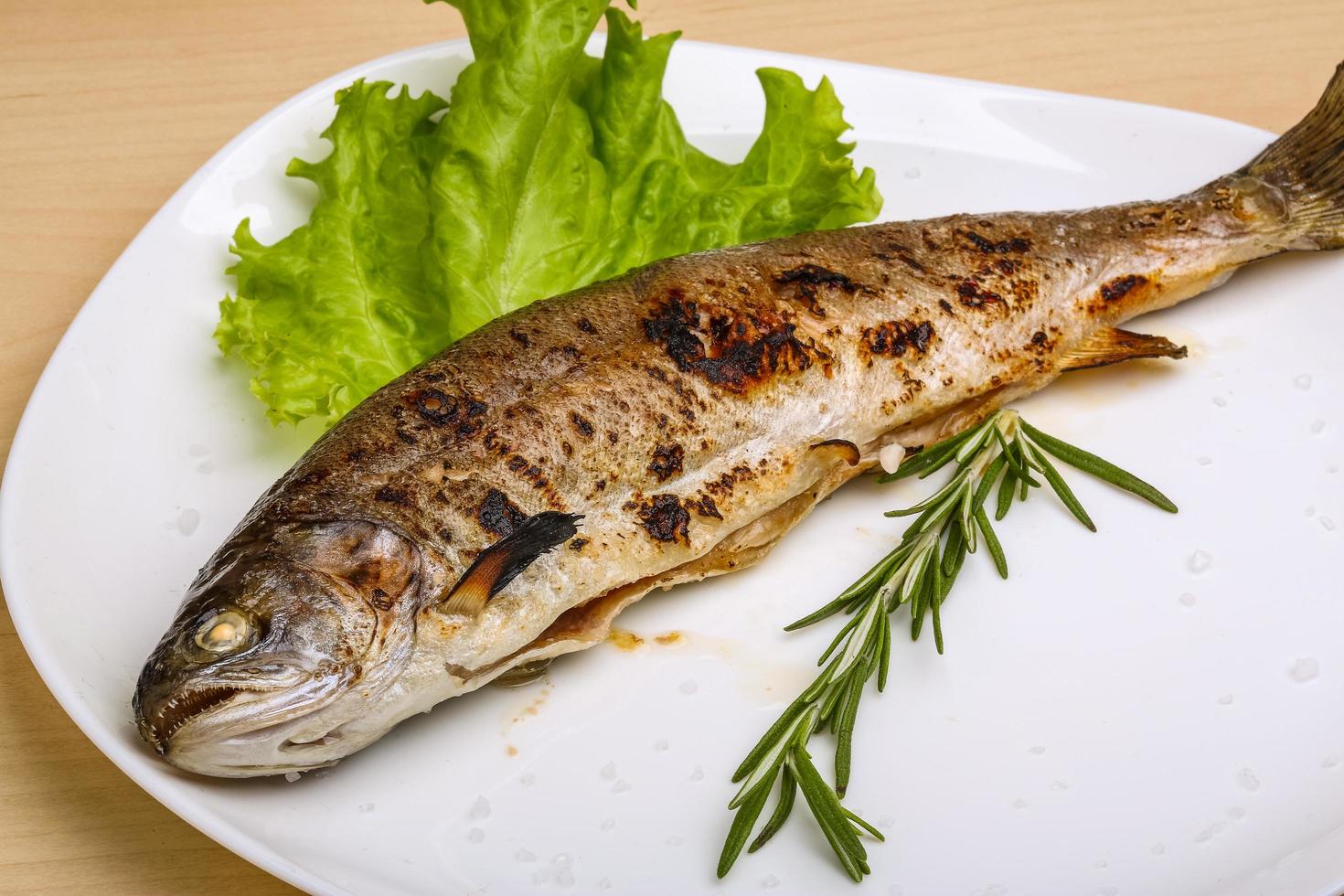 Grilled trout on the plate and wooden background photo