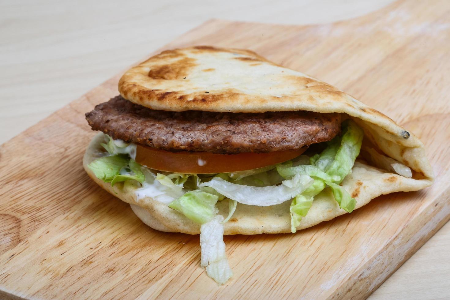 Greek pita on wooden board and wooden background photo