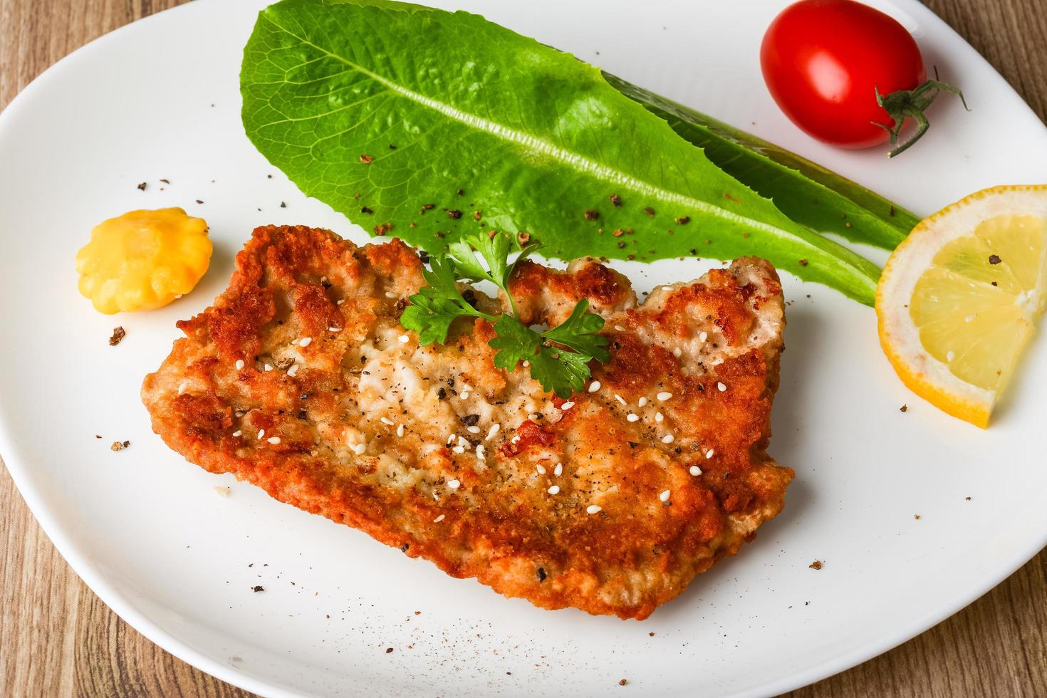 Pork schnitzel on the plate and wooden background photo