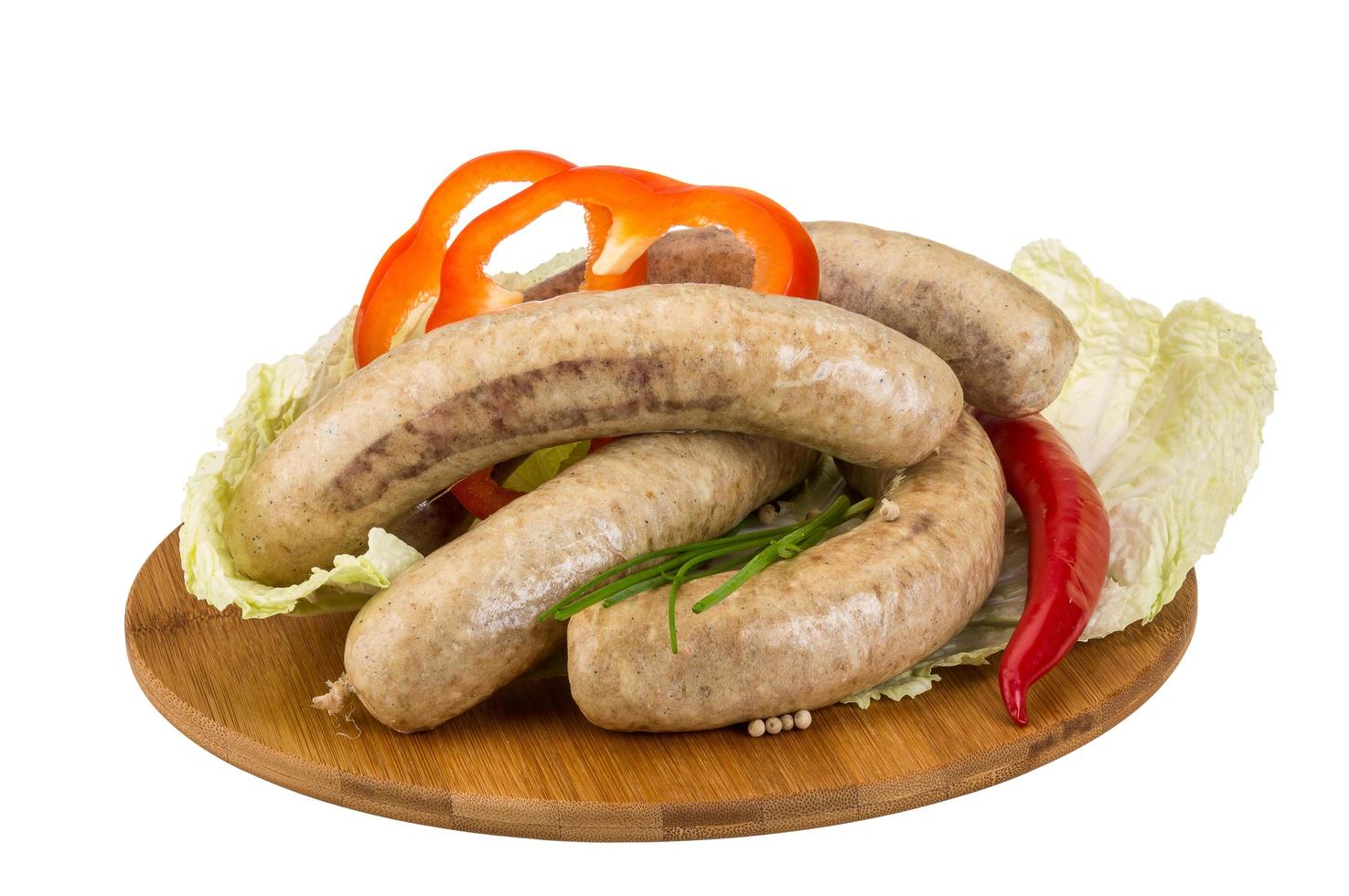 Grilled sausages on wooden board and white background photo