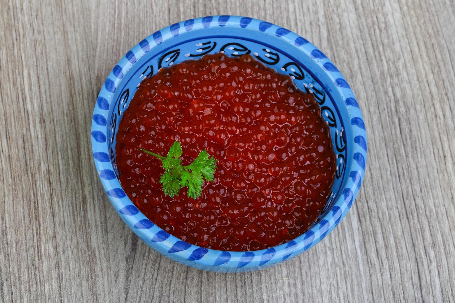 Red caviar in a bowl on wooden background photo