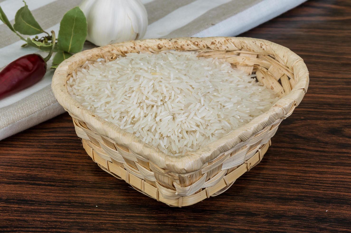 Basmati rice in a basket on wooden background photo