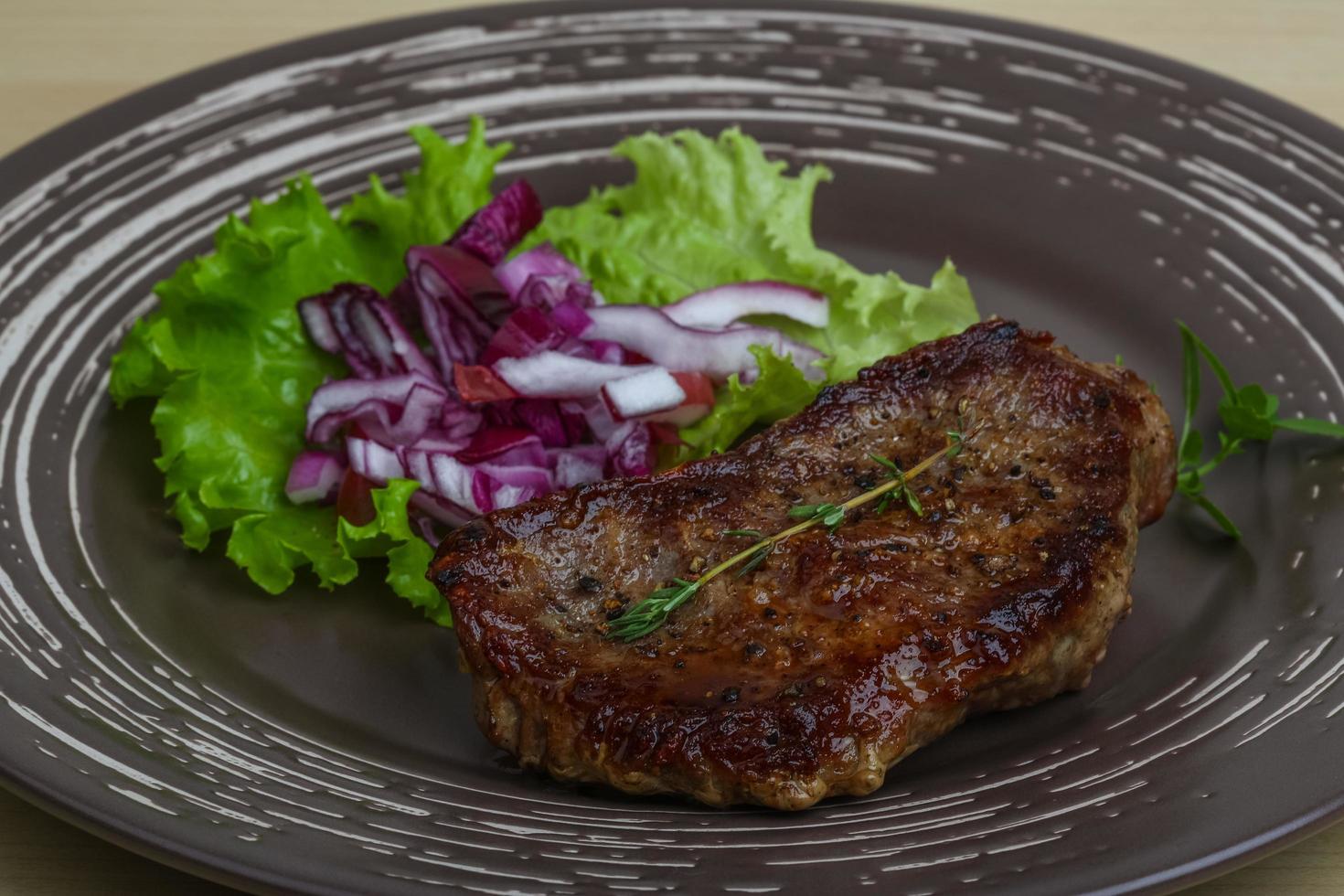 bistec en el plato y fondo de madera foto