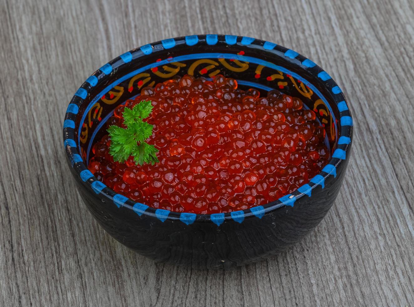 Red caviar in a bowl on wooden background photo