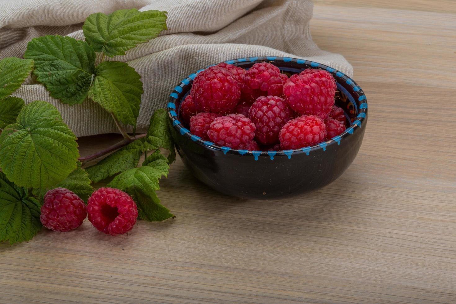 Fresh raspberry in a bowl on wooden background photo