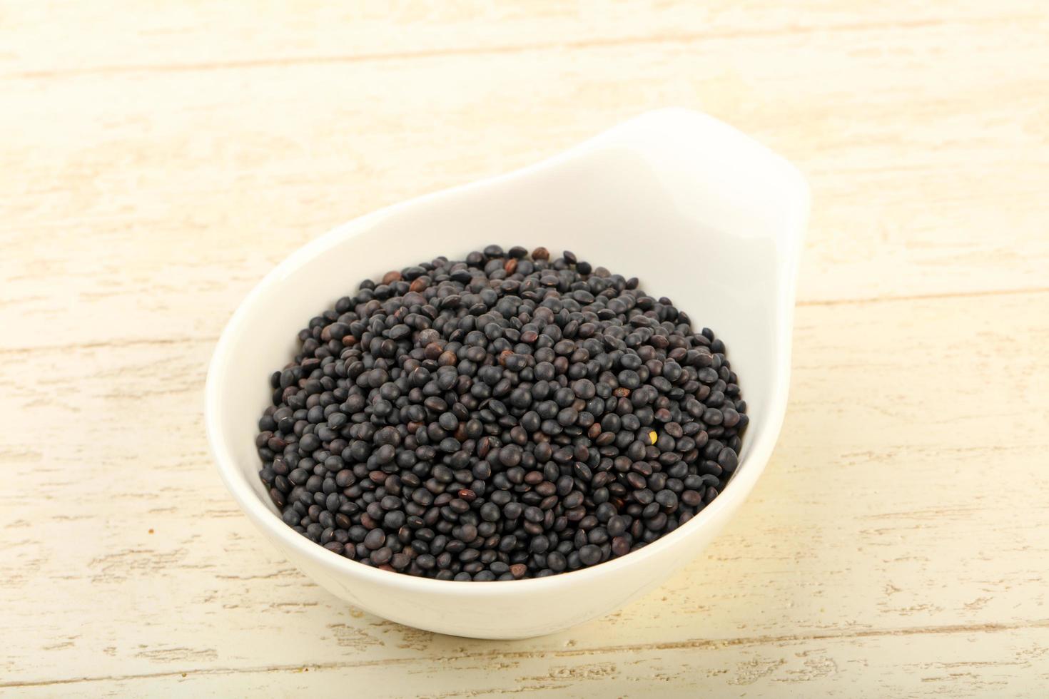 Black lentils in a bowl on wooden background photo