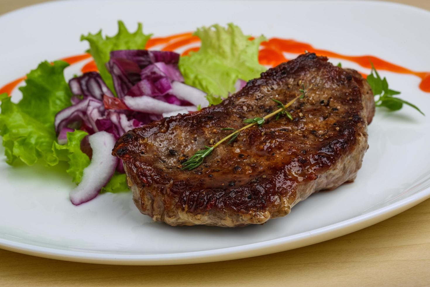 bistec en el plato y fondo de madera foto