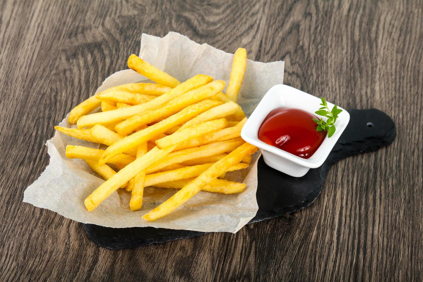 patatas fritas en el plato y fondo de madera foto