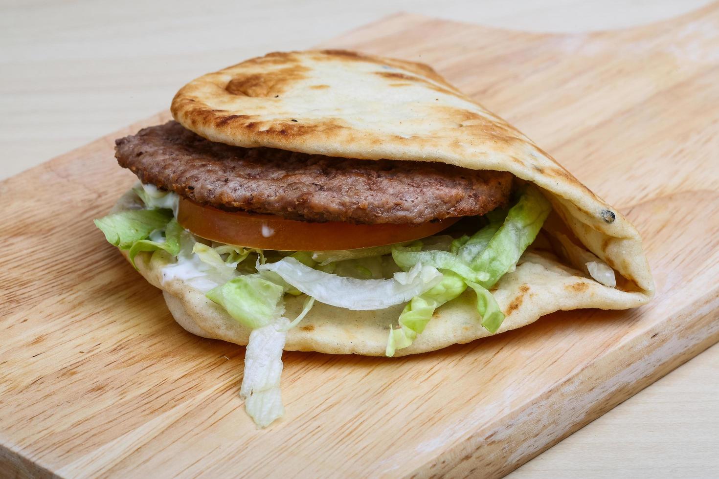 Greek pita on wooden board and wooden background photo