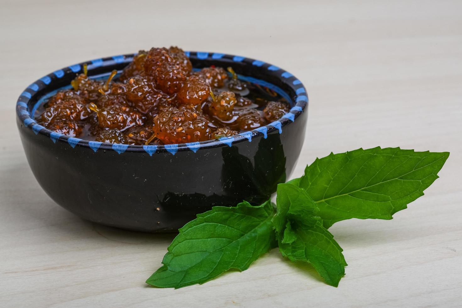 Mulberry jam in a bowl on wooden background photo