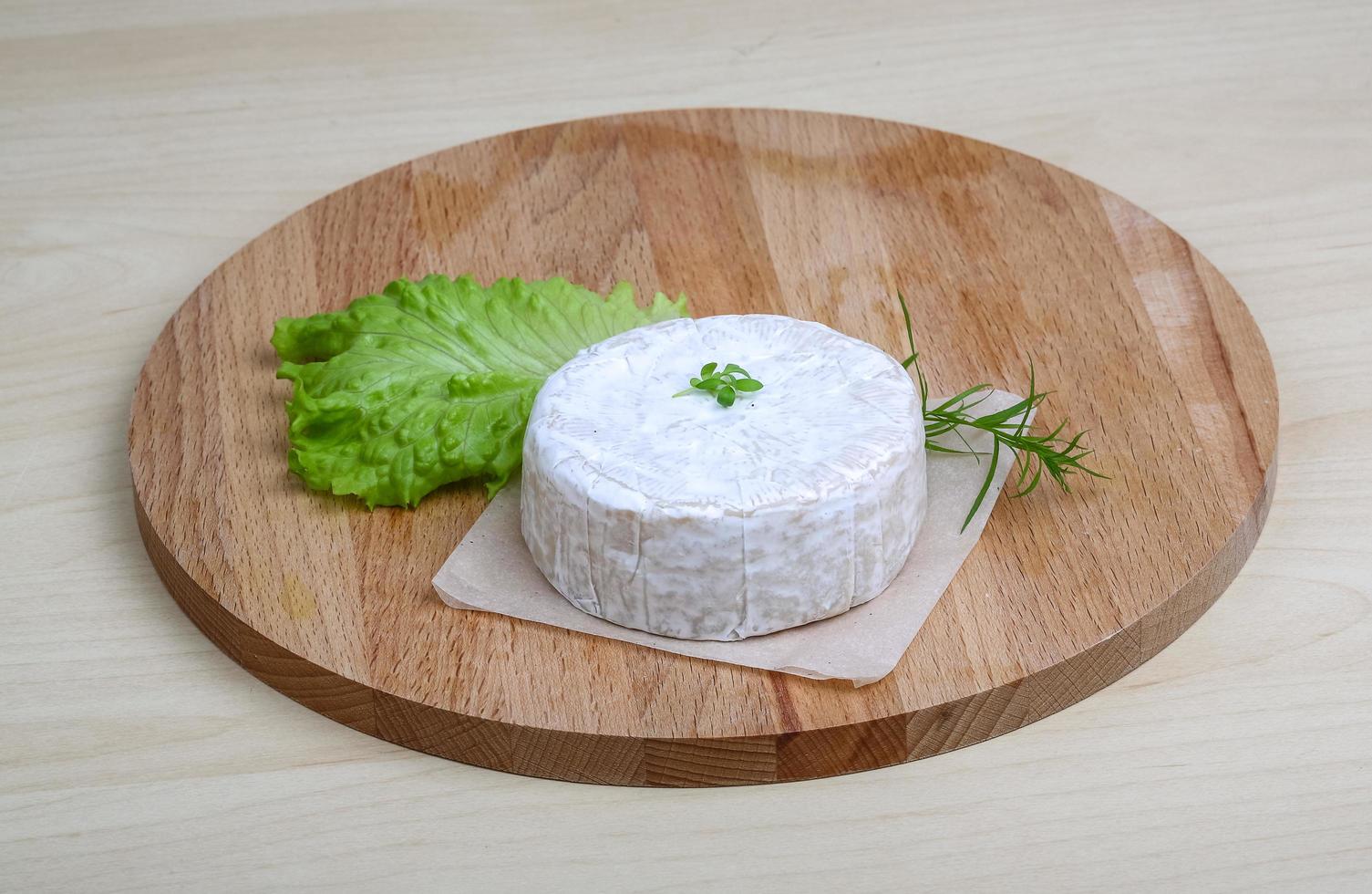 Brie cheese on wooden board and wooden background photo