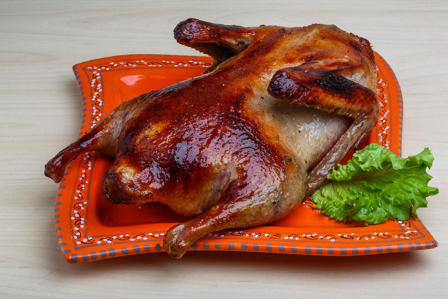 pato asado en el plato y fondo de madera foto