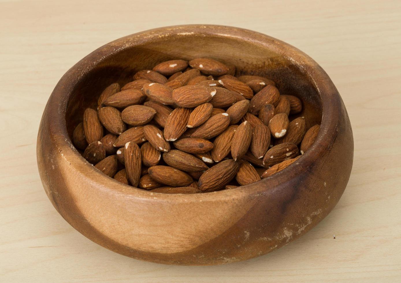 almendras en un bol sobre fondo de madera foto