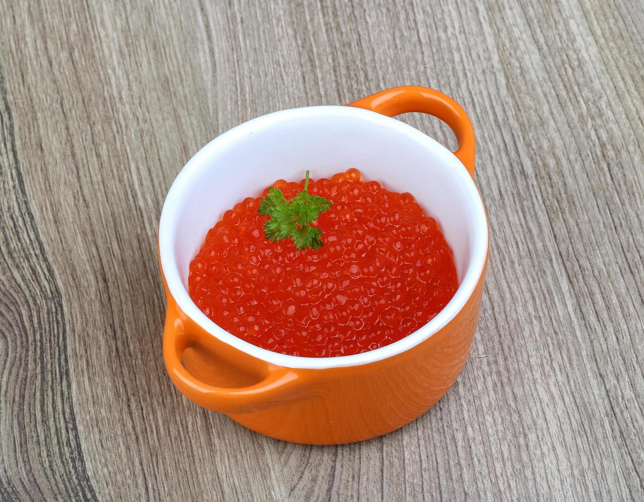 caviar rojo en un recipiente sobre fondo de madera foto