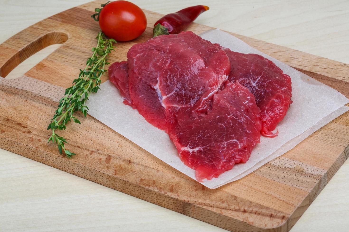 Raw beef on wooden board and wooden background photo