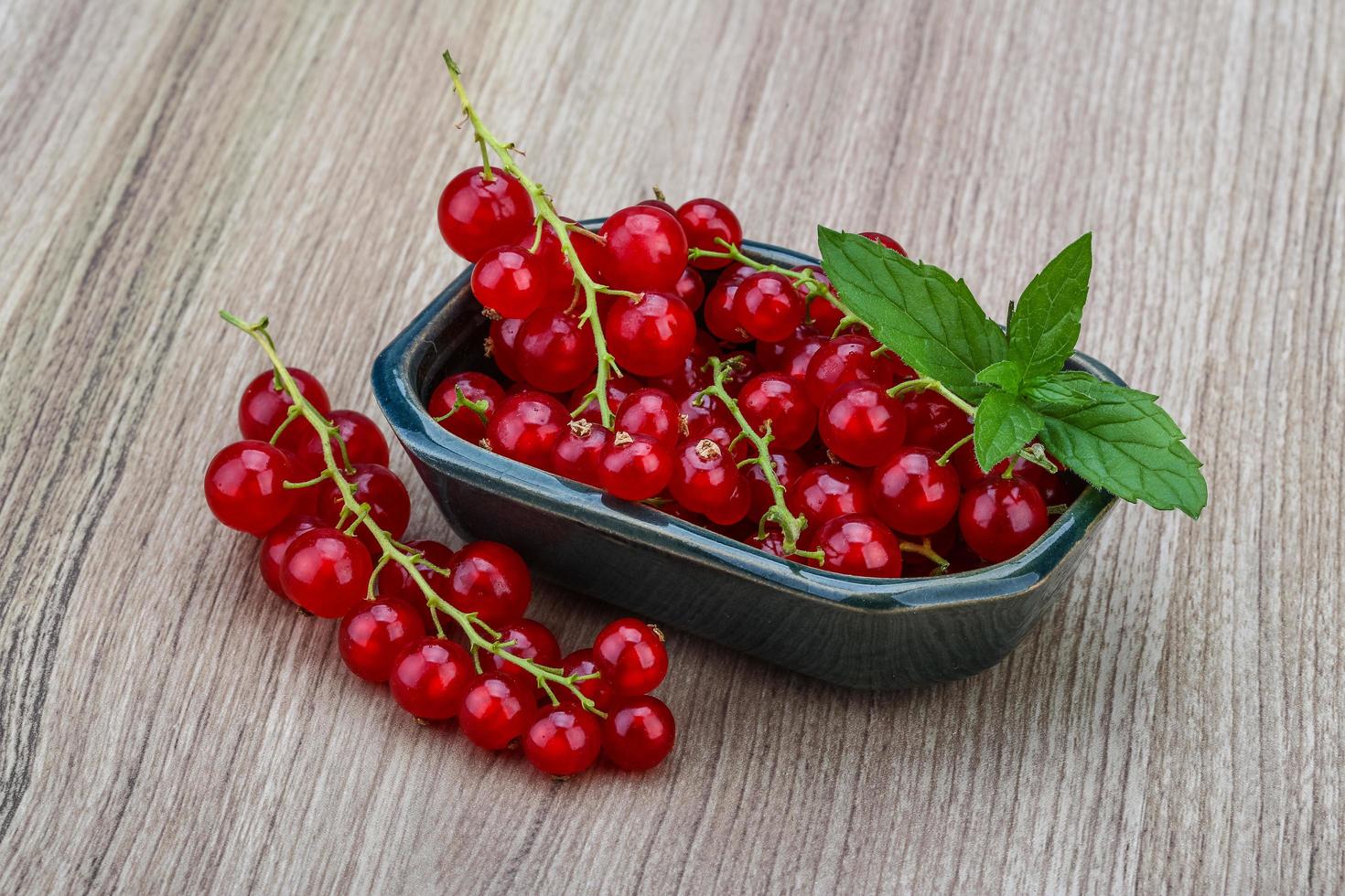 Red currants in a bowl on wooden background photo