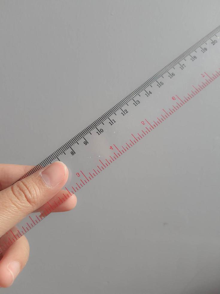 A hand is holding a plastic ruler. photo