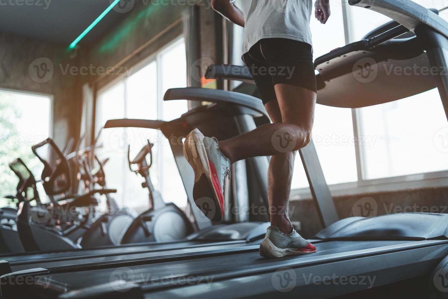Close up of feet, sportman runner running on treadmill in fitness club. Cardio workout. Healthy lifestyle, guy training in gym. Sport running concept photo