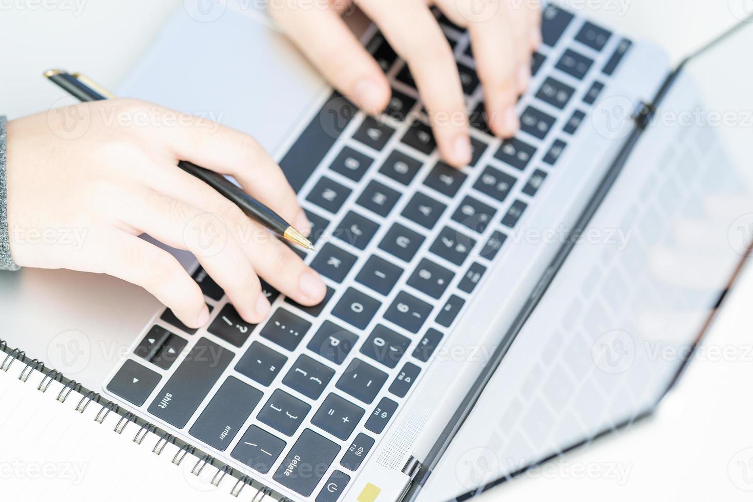 Woman working at home office using laptop searching web, browsing information photo