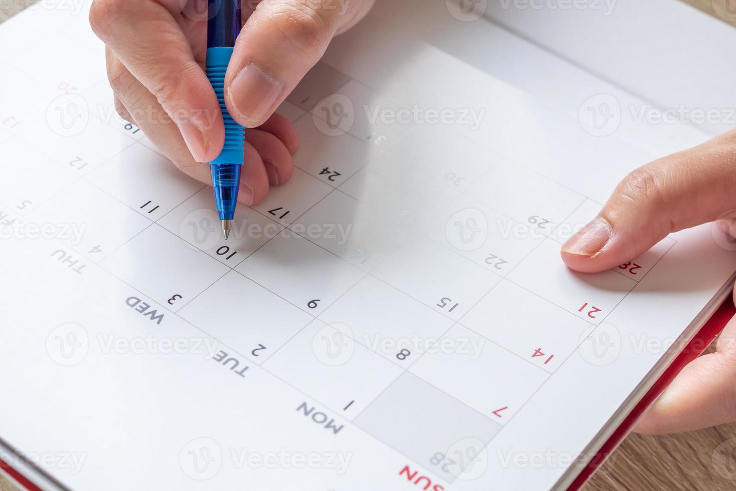 Woman hand with pen writing on calendar date business planning appointment meeting concept photo