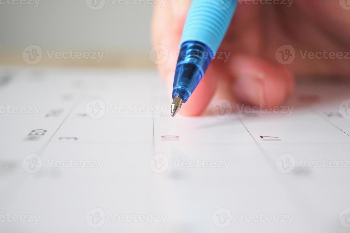 mano de mujer con bolígrafo escribiendo en la fecha del calendario concepto de reunión de cita de planificación empresarial foto