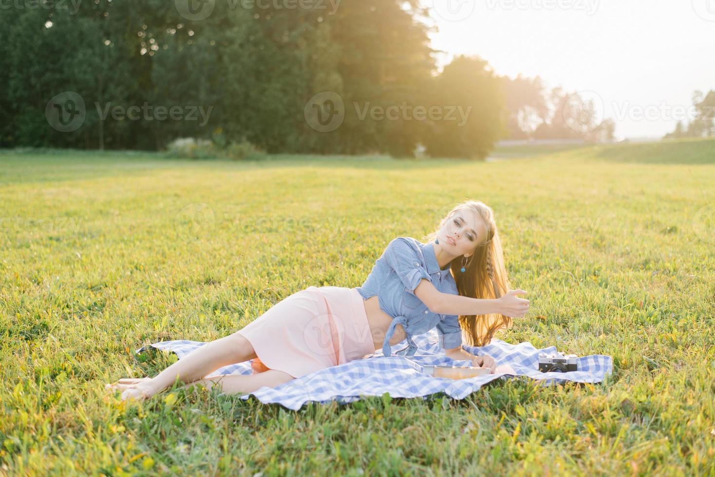 Young cute girl lies on a blanket in nature and enjoys holidays weekends photo
