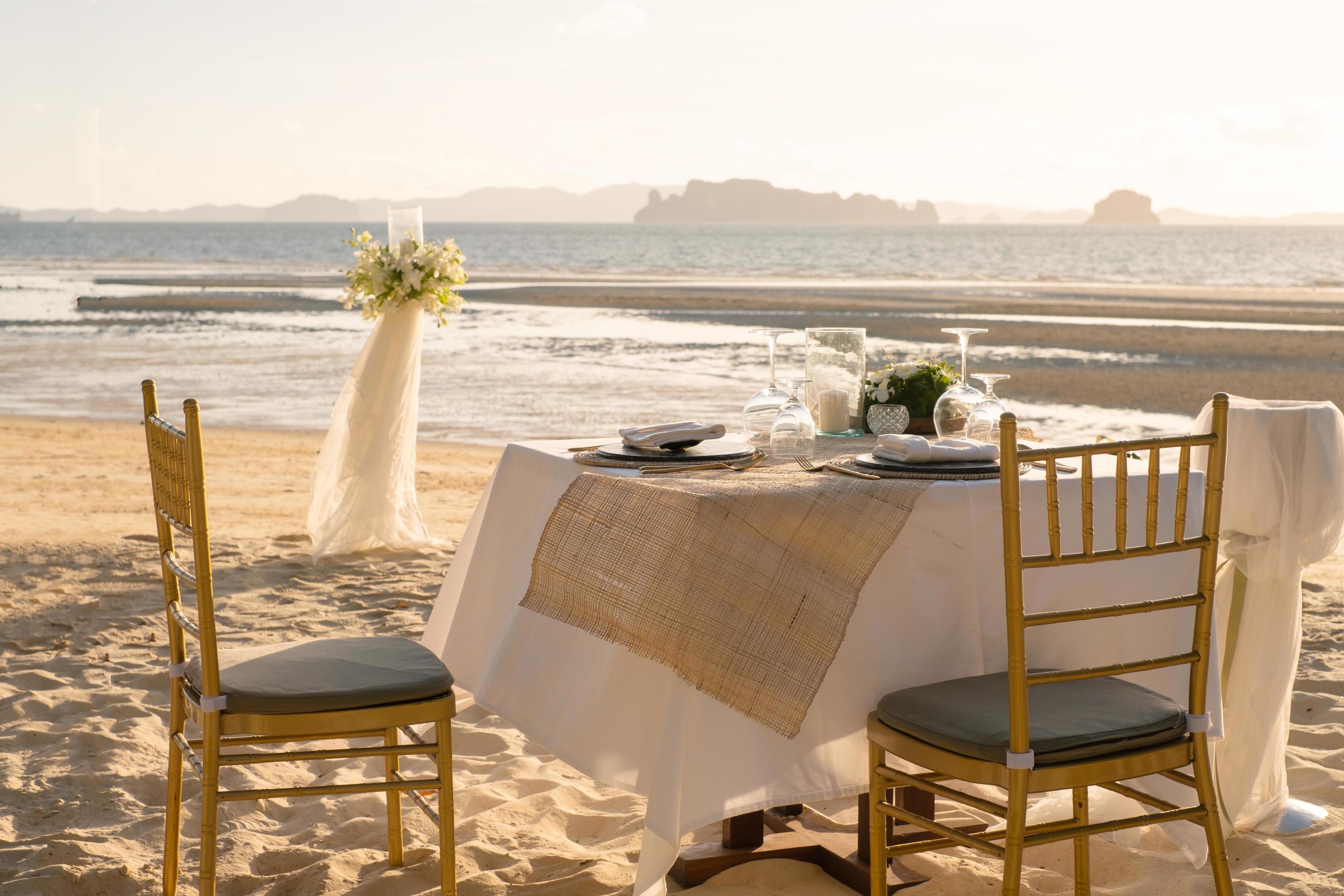hermosa mesa preparada para una cena romántica en la playa con flores y