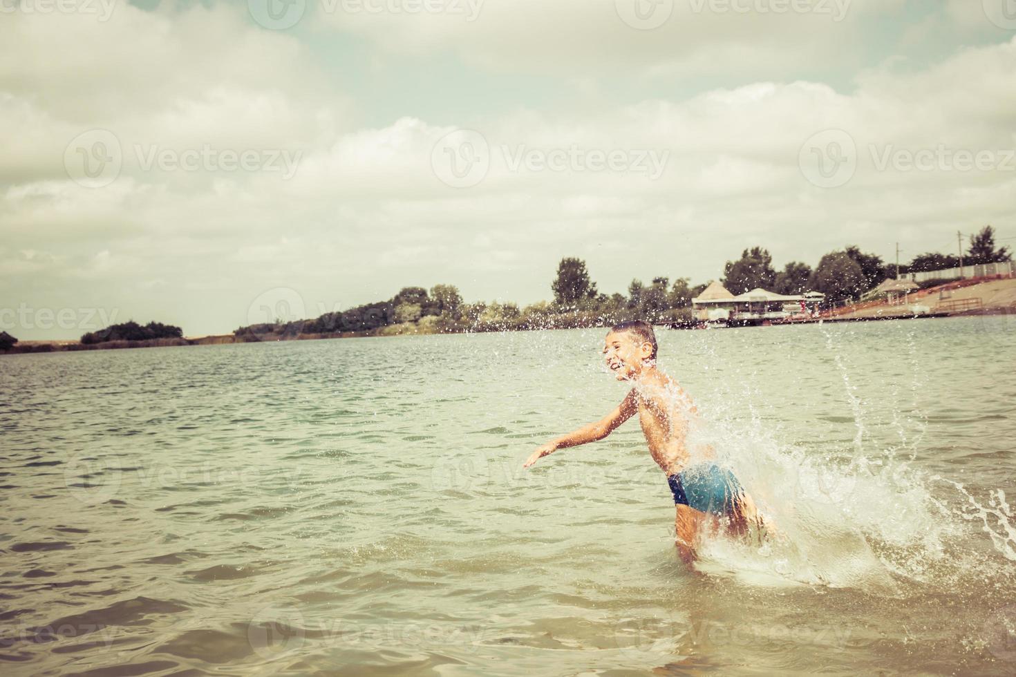 Carefree boy running in the water during summer day. photo
