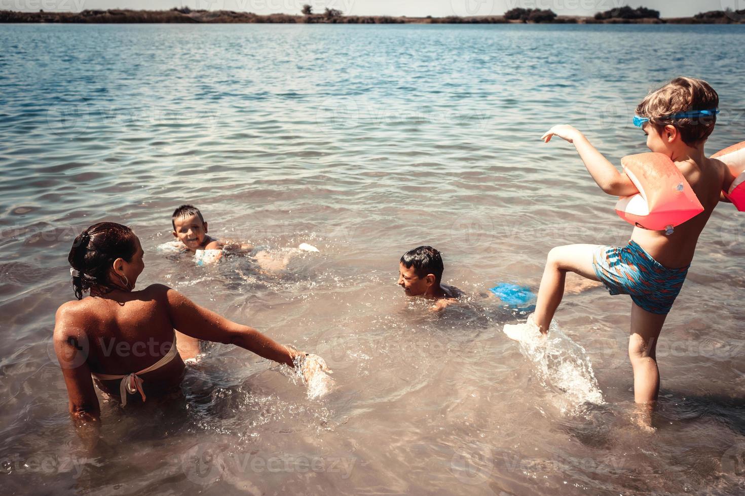 Playful kids and their mother having fun on the beach in summer. photo