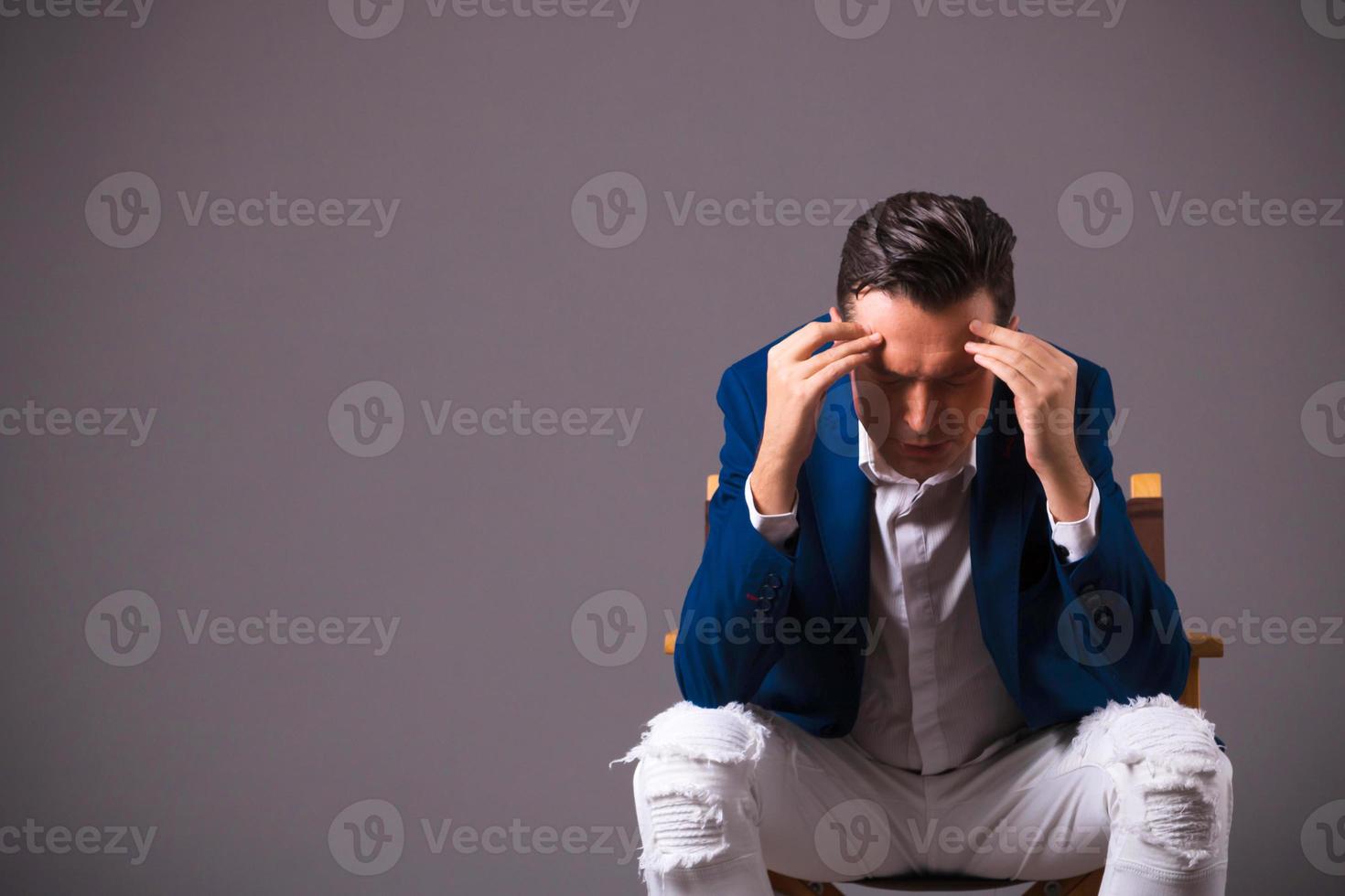 Stressed businessman holding his head in pain against gray background. photo