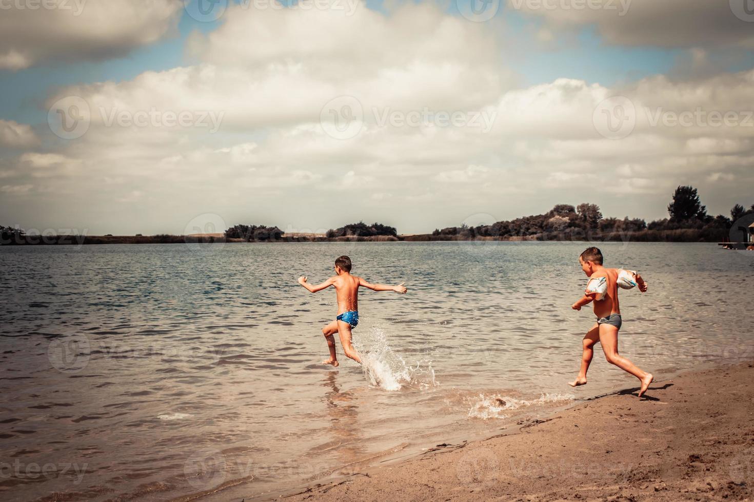 Small kids having fun while running in the sea in summer day. photo