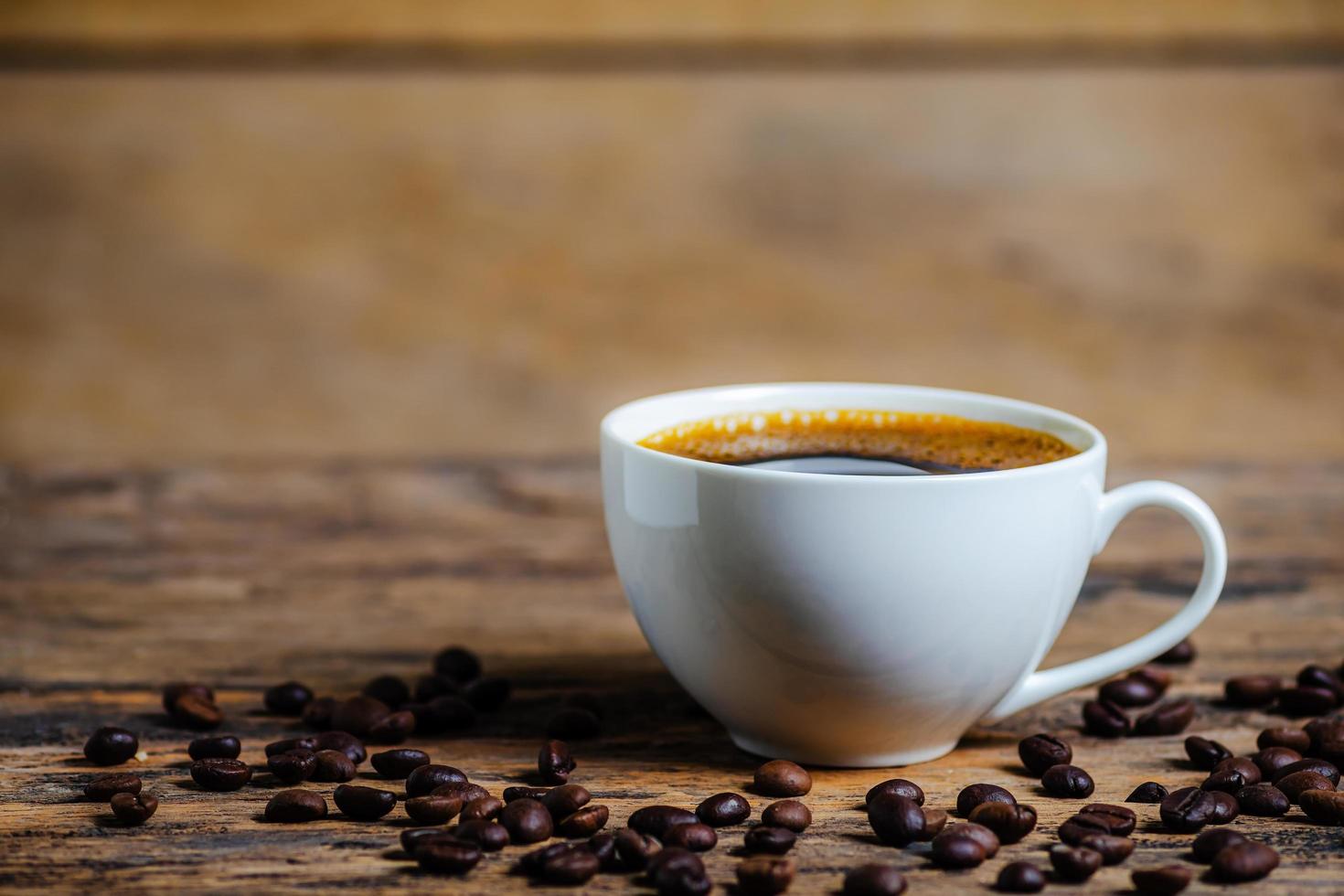 A cup of coffee with coffee bean on wooden background photo