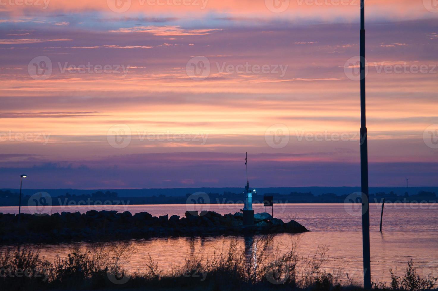 Sunset in Sweden at the harbor of lake Vaettern. Lighthouse in the background photo