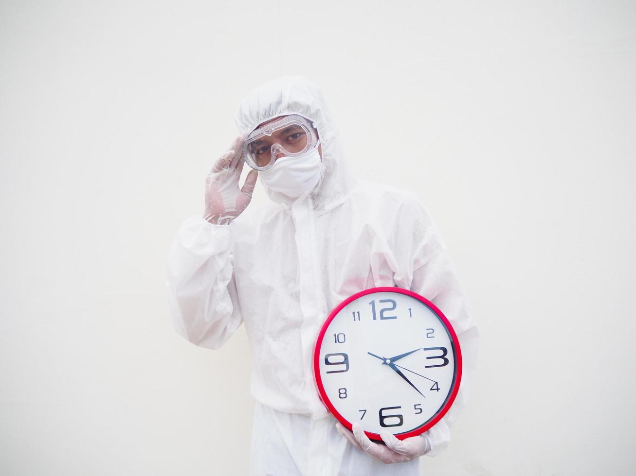 Portrait of doctor or scientist in PPE suite uniform holding red alarm clock and looking at the camera In various gestures. COVID-19 concept isolated white background photo