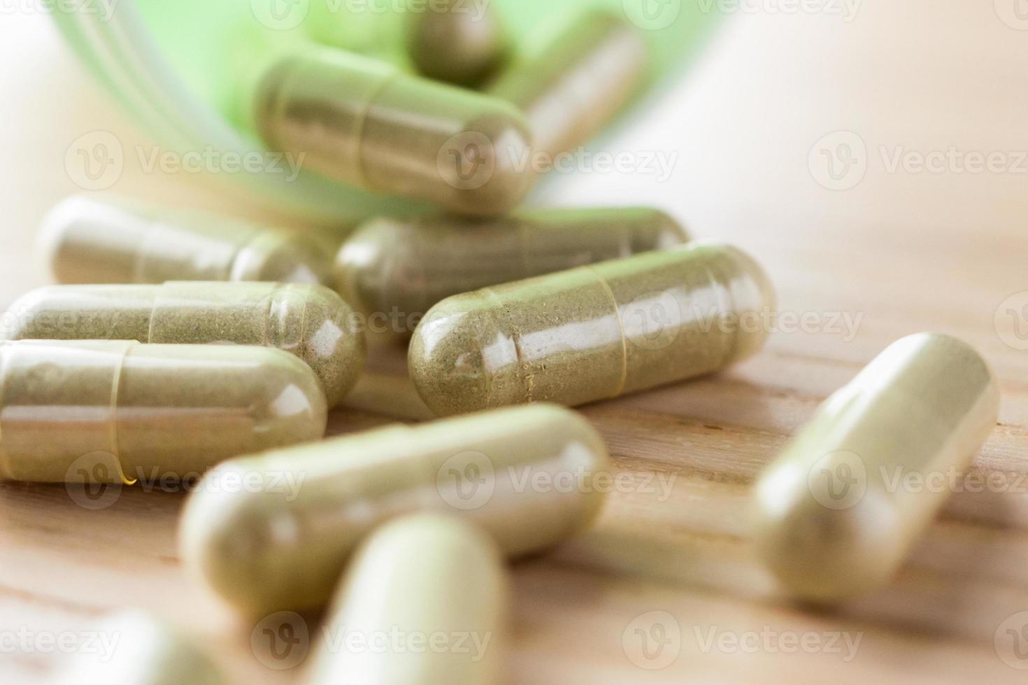 Herbal medicine capsules with bottle on wood table photo