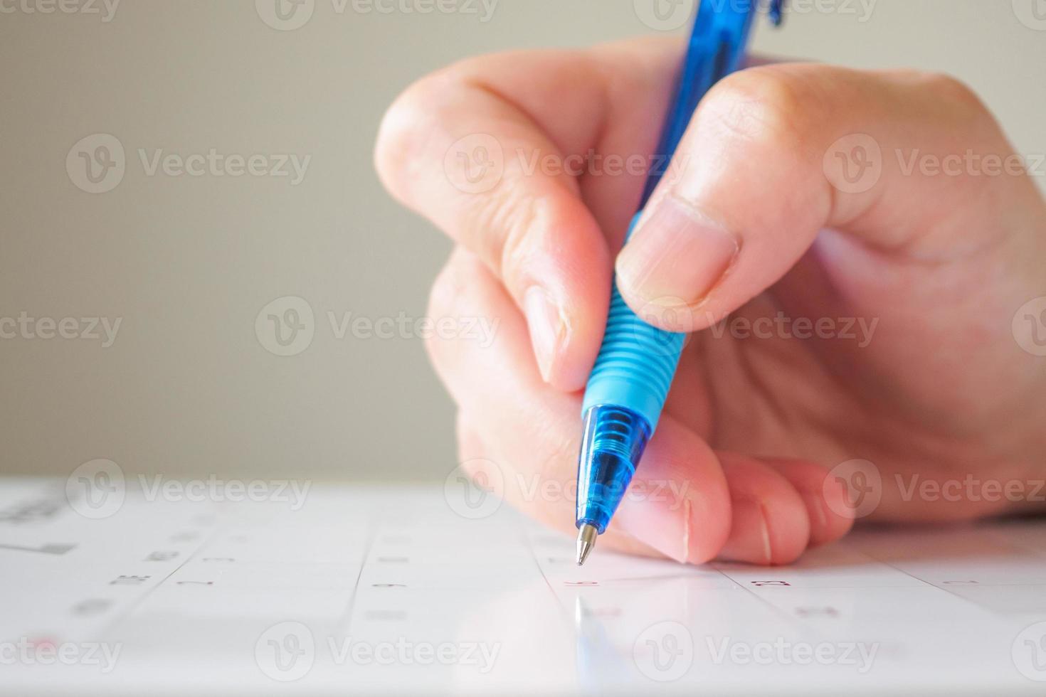 Woman hand with pen writing on calendar date business planning appointment meeting concept photo