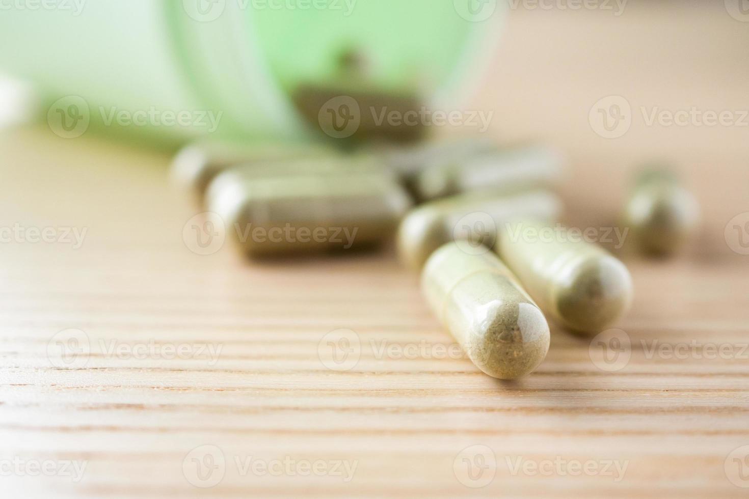 Herbal medicine capsules with bottle on wood table photo