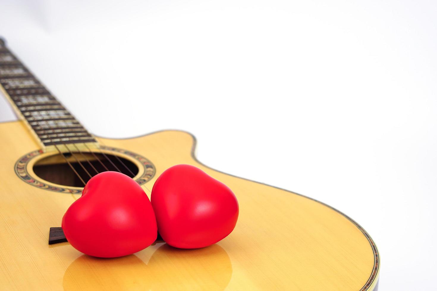 Acoustic guitar and red heart on a white background. Love and music concept. photo