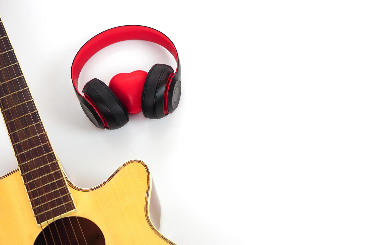 Acoustic guitar, headphones and red heart on a white background. Love and music concept. photo