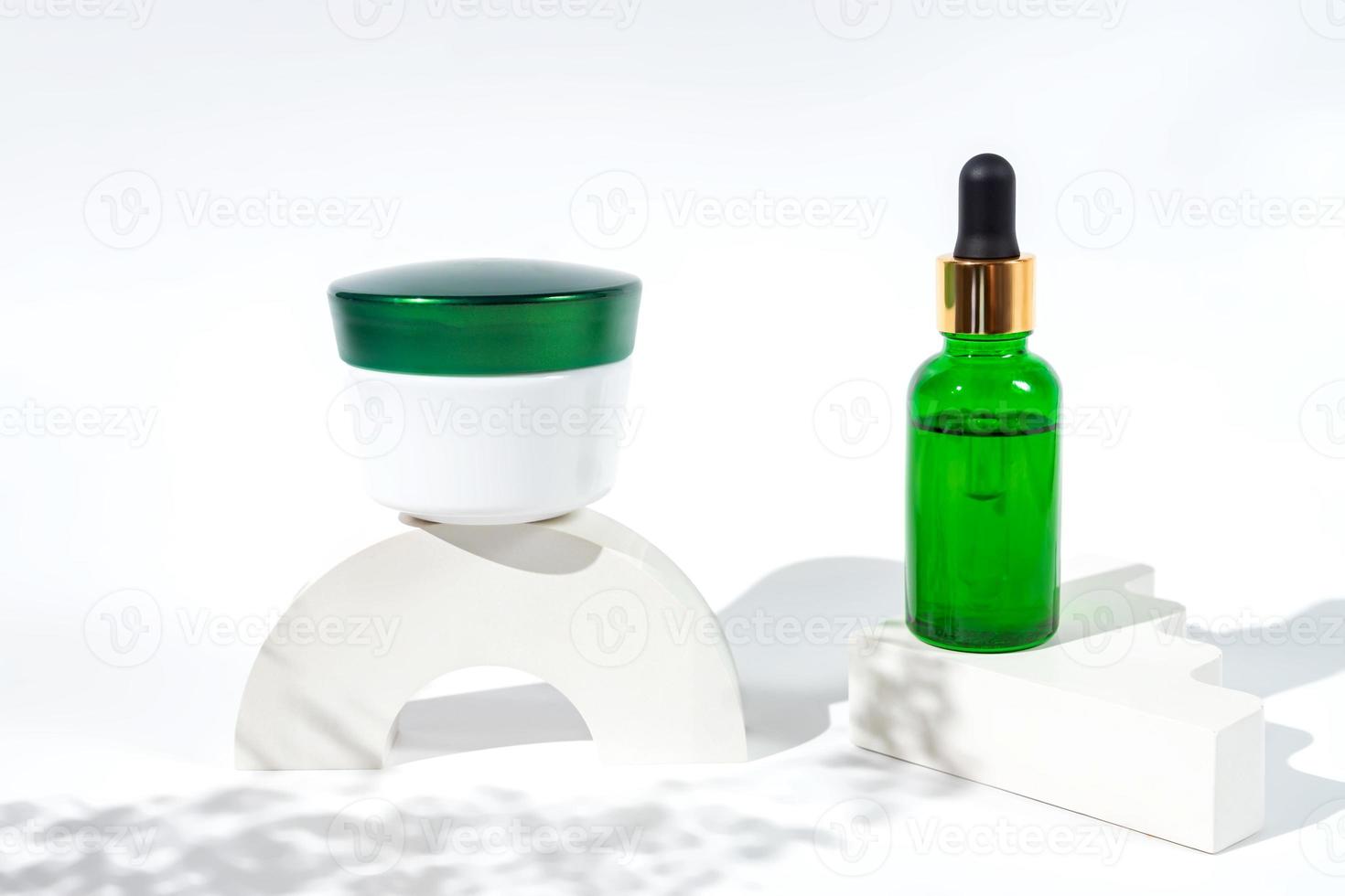 Set of natural cosmetics for face care serum bottle and cream on concrete podiums on white background with harsh shadows. Trendy concept of skincare products photo