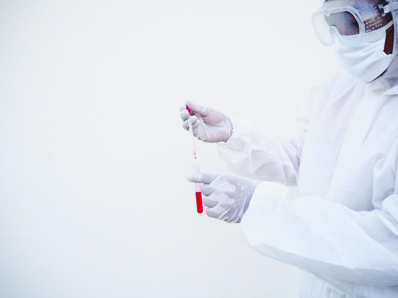 Asian doctor or scientist in PPE suite uniform. Personal protective equipment suit dropping a blood into blood test tube. coronavirus or COVID-19 concept isolated white background photo