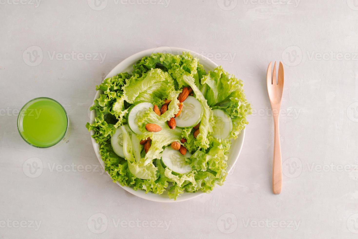 Fresh salad with tomatoes, cucumbers and lettuce on a wooden background photo