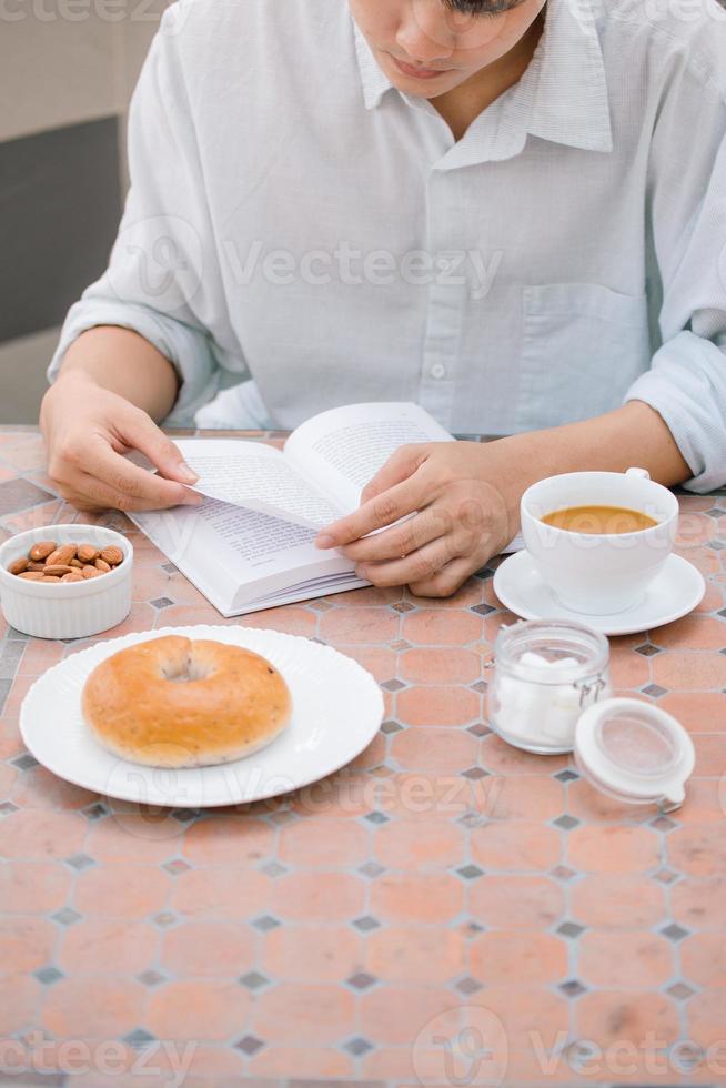 Portrait of a handsome man reading a book and enjoying his coffee. photo