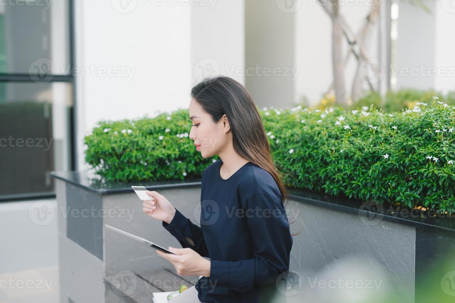 una mujer de negocios asiática bastante joven en un banco fuera del edificio de oficinas foto