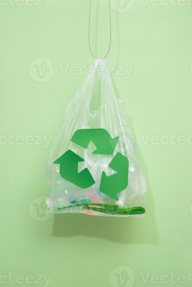 waste recycling, reuse, garbage disposal, environment and ecology concept - close up of rubbish bag with trash or garbage and green recycle symbol at home photo