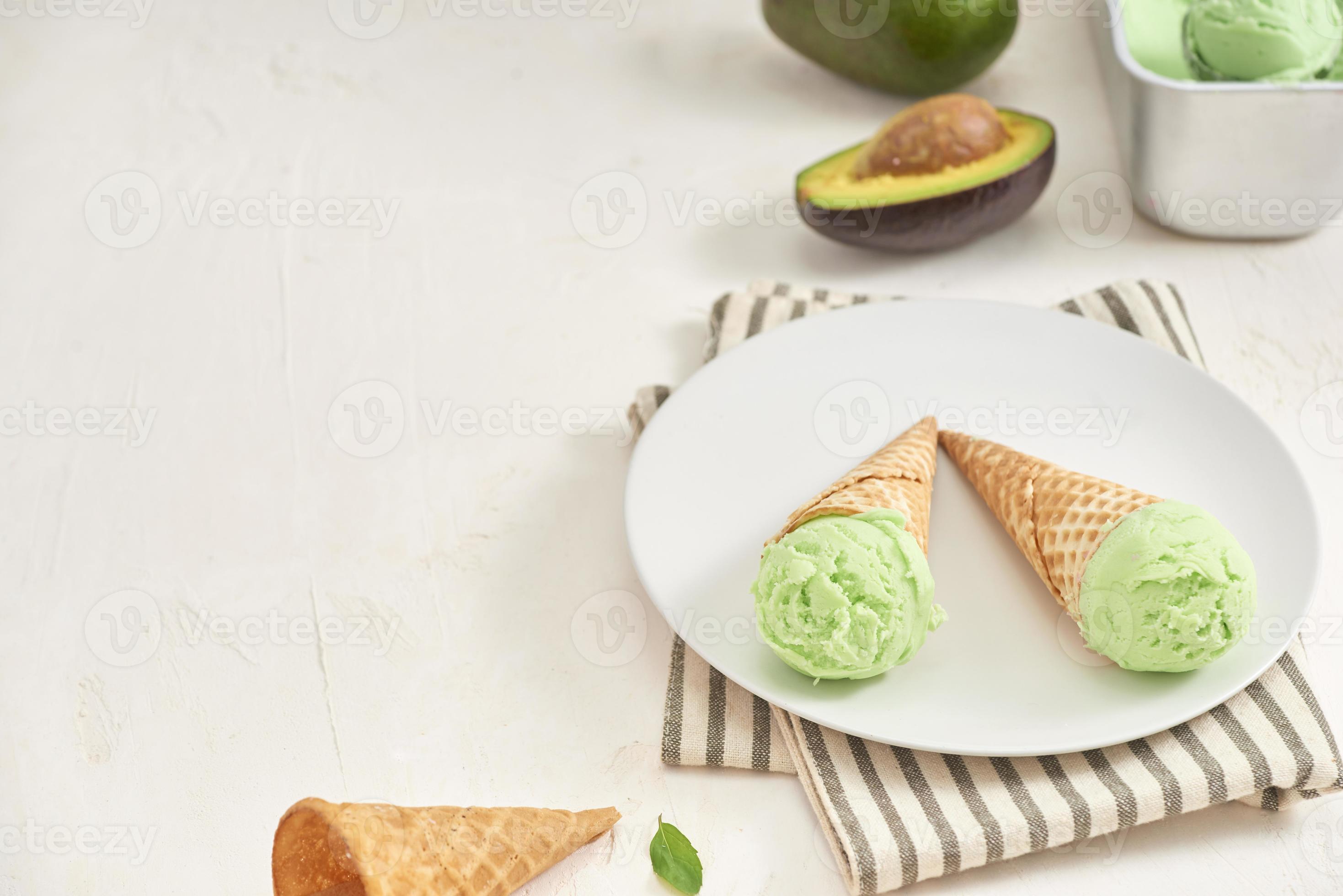 Green avocado ice cream scoops in wafle cones on white background. Copy