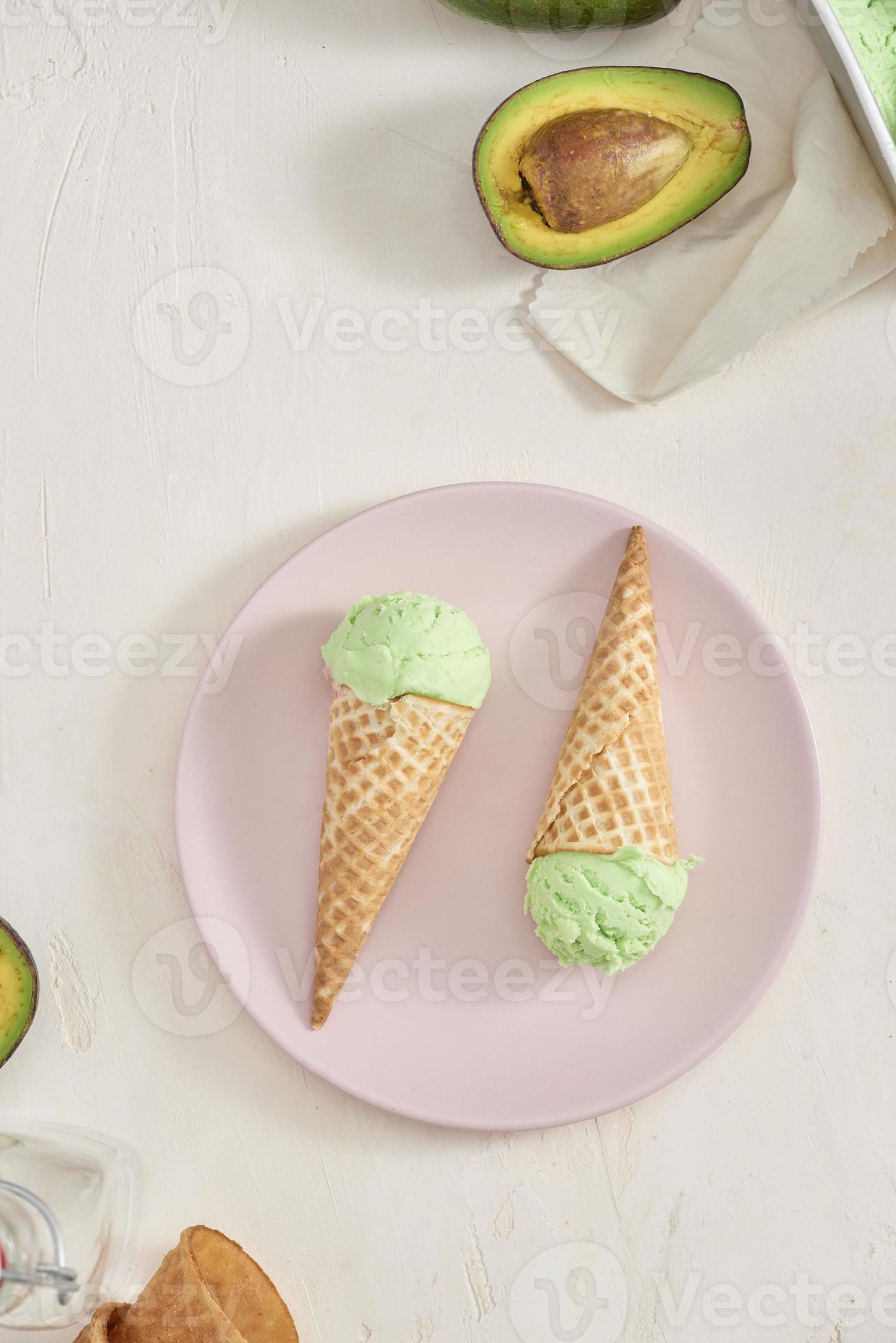 Green avocado ice cream scoops in wafle cones on white background. Copy