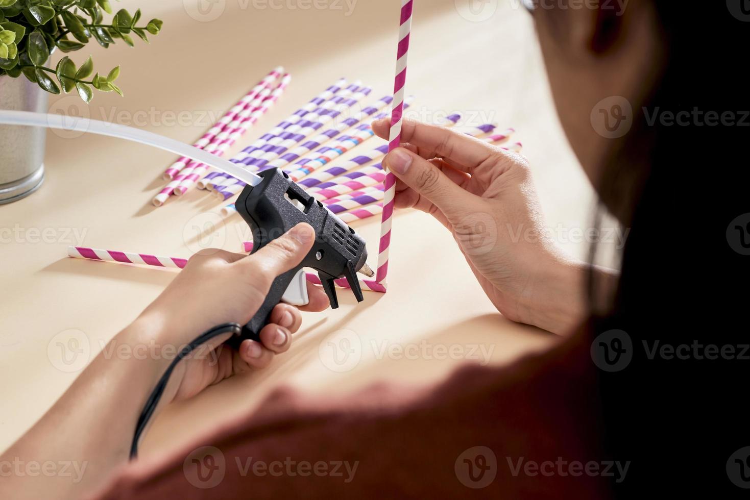 Glue gun in the woman's hand. Woman glues straws with a glue gun. closeup photo
